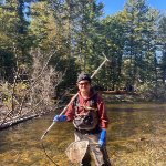 Graduate student Michael Trapp poses in a stream with a net and backpack electrofishing gear. on December 10, 2025